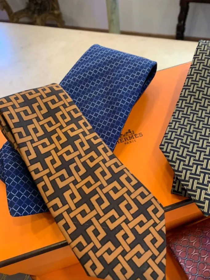 Cravates en soie Hermès posées sur leur boîte orange